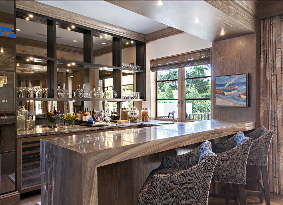Diseño de bar en casa con barra de bar clásico renovado extra grande con encimera de mármol, salpicadero con efecto espejo y suelo de madera en tonos medios