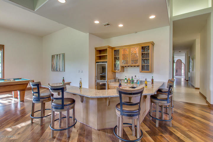 Photo of a large traditional u-shaped breakfast bar in Phoenix with a submerged sink, glass-front cabinets, light wood cabinets, granite worktops, beige splashback and dark hardwood flooring.