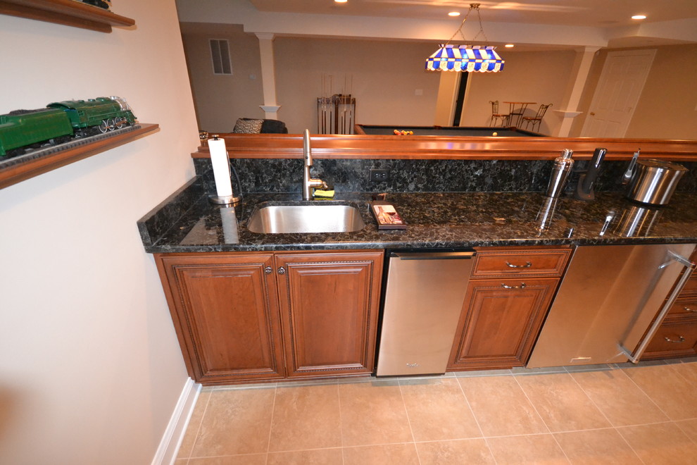Large elegant l-shaped ceramic tile seated home bar photo in Philadelphia with an undermount sink, raised-panel cabinets, medium tone wood cabinets and granite countertops