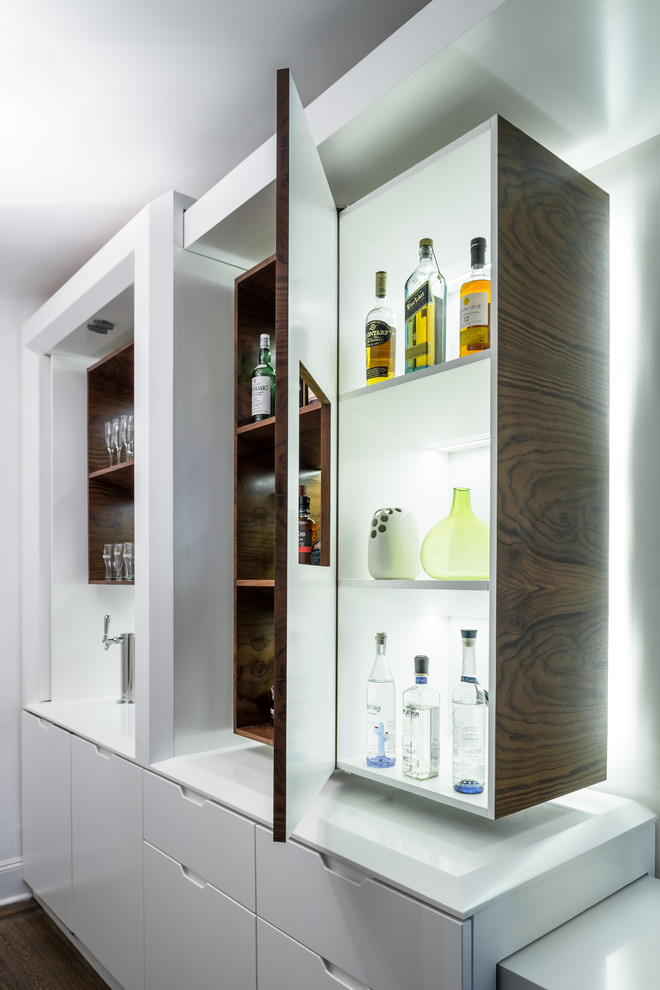 Immagine di un angolo bar design con ante lisce, ante bianche, parquet scuro, pavimento marrone e top bianco