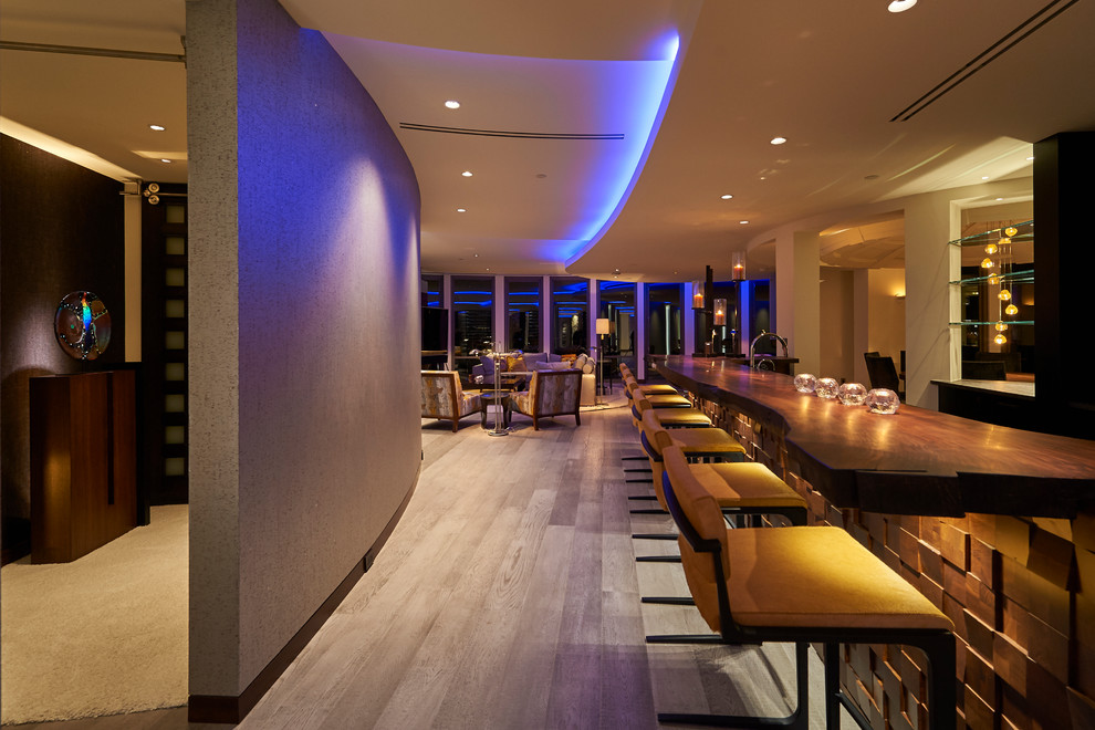 Example of a large trendy galley light wood floor and gray floor wet bar design in Other with dark wood cabinets and wood countertops