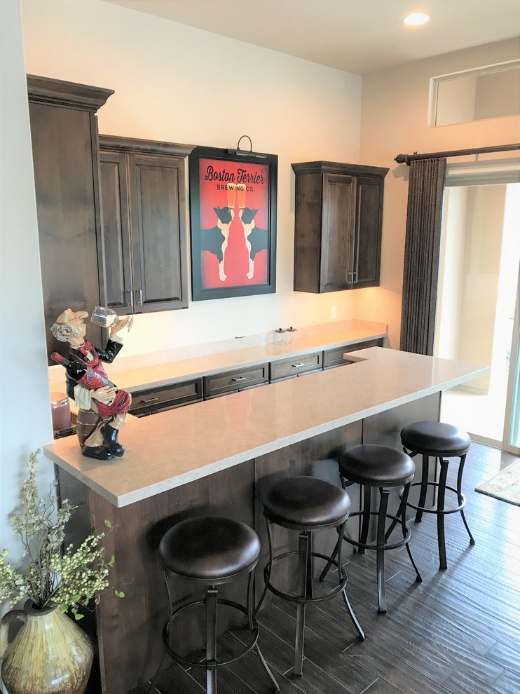 Example of a mid-sized classic u-shaped dark wood floor and brown floor seated home bar design in Phoenix with raised-panel cabinets, dark wood cabinets and quartz countertops