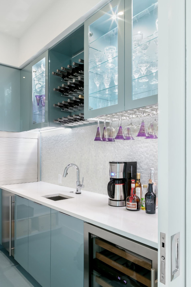 Modern inredning av en mellanstor vita l-formad vitt hemmabar med vask, med en undermonterad diskho, släta luckor, blå skåp, vitt stänkskydd och blått golv