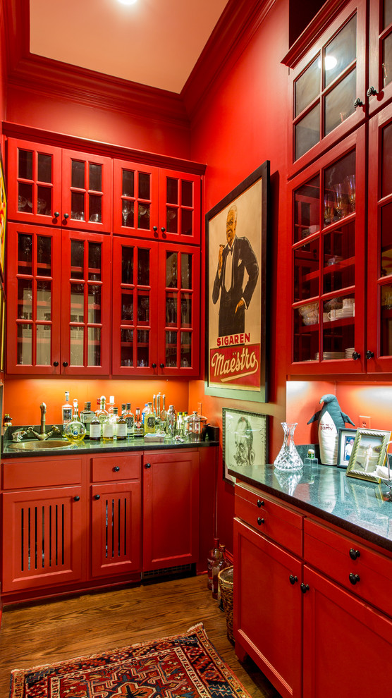 Cette photo montre un bar de salon avec évier linéaire chic avec un évier posé, un placard à porte vitrée, des portes de placard rouges, une crédence rouge et parquet foncé.