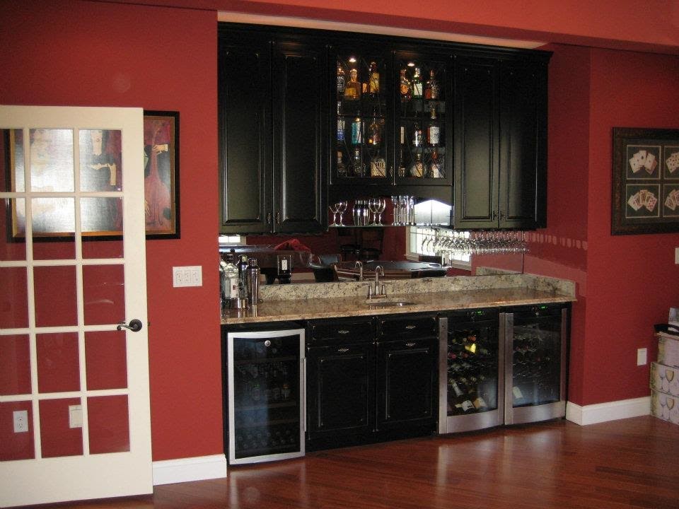 Photo of a medium sized classic single-wall wet bar in New York with a submerged sink, raised-panel cabinets, black cabinets, granite worktops, mirror splashback and medium hardwood flooring.