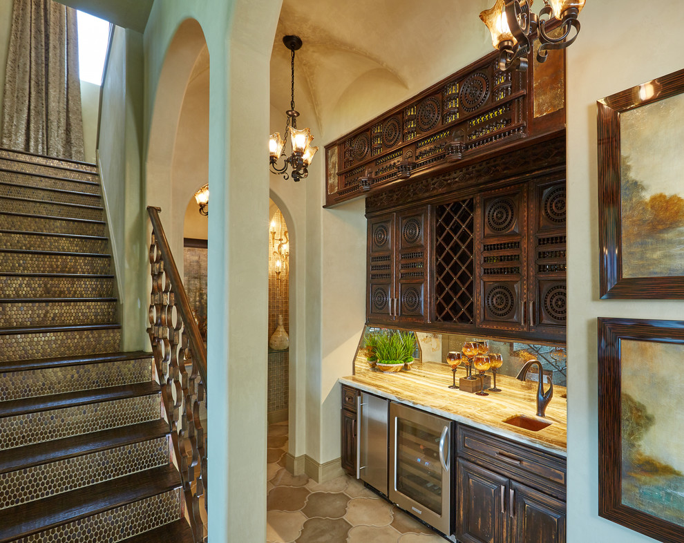 Inspiration for a mediterranean single-wall concrete floor and beige floor home bar remodel in Dallas with an undermount sink, dark wood cabinets, limestone countertops, multicolored backsplash, mirror backsplash and beige countertops