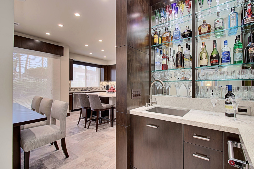 This is an example of a medium sized contemporary l-shaped wet bar in Los Angeles with a submerged sink, flat-panel cabinets, dark wood cabinets, granite worktops, stone slab splashback and porcelain flooring.
