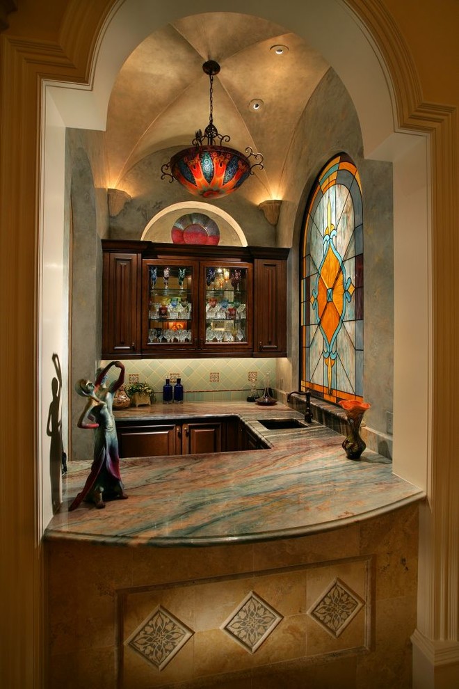 This is an example of a victorian u-shaped wet bar in Miami with raised-panel cabinets, dark wood cabinets and green splashback.