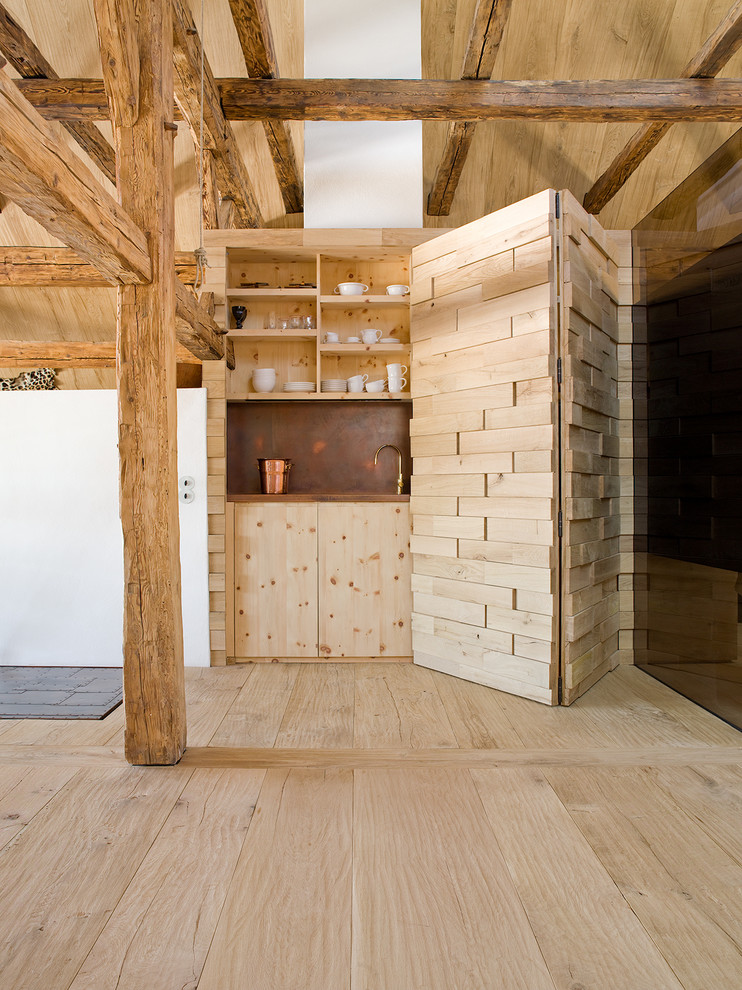 Rustik inredning av en liten linjär hemmabar med vask, med ljust trägolv, släta luckor, skåp i ljust trä, brunt stänkskydd och beiget golv