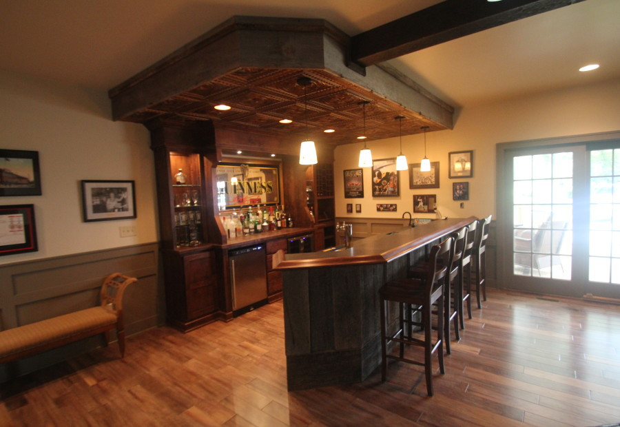 Seated home bar - large traditional medium tone wood floor seated home bar idea in Cleveland with an undermount sink, raised-panel cabinets, medium tone wood cabinets and granite countertops