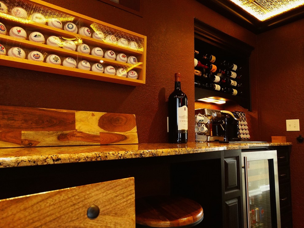 Seated home bar - mid-sized traditional medium tone wood floor seated home bar idea in Milwaukee with raised-panel cabinets, black cabinets and granite countertops