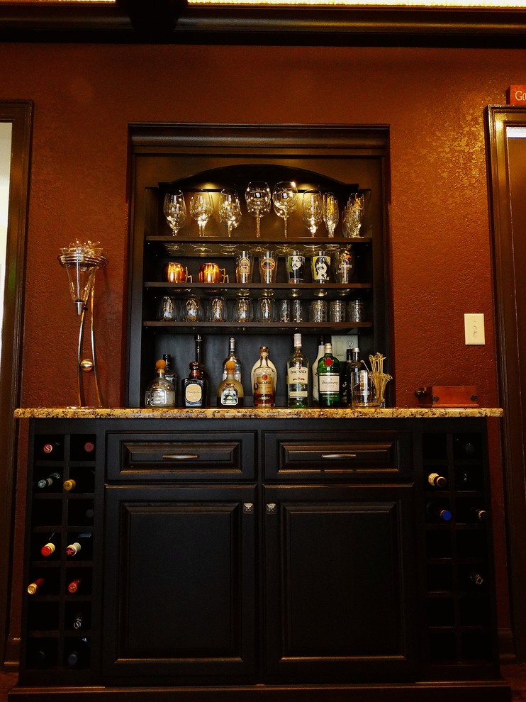 Ispirazione per un bancone bar classico di medie dimensioni con ante con bugna sagomata, ante nere, top in granito e pavimento in legno massello medio