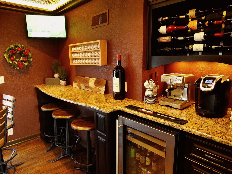 Inspiration for a mid-sized timeless medium tone wood floor seated home bar remodel in Milwaukee with raised-panel cabinets, black cabinets and granite countertops