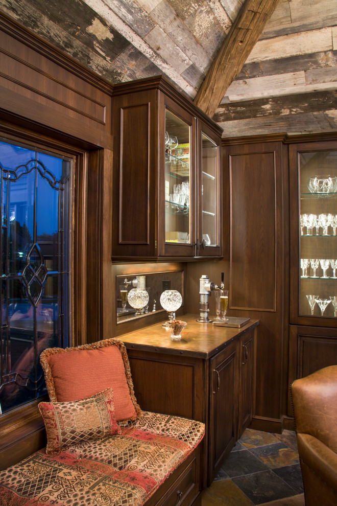 Idée de décoration pour un bar de salon bohème en bois foncé avec des tabourets, un placard à porte vitrée, un plan de travail en cuivre et une crédence miroir.