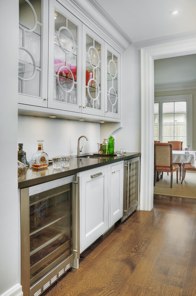 Design ideas for a large traditional single-wall wet bar in Toronto with a submerged sink, recessed-panel cabinets, grey cabinets, engineered stone countertops, medium hardwood flooring and brown floors.