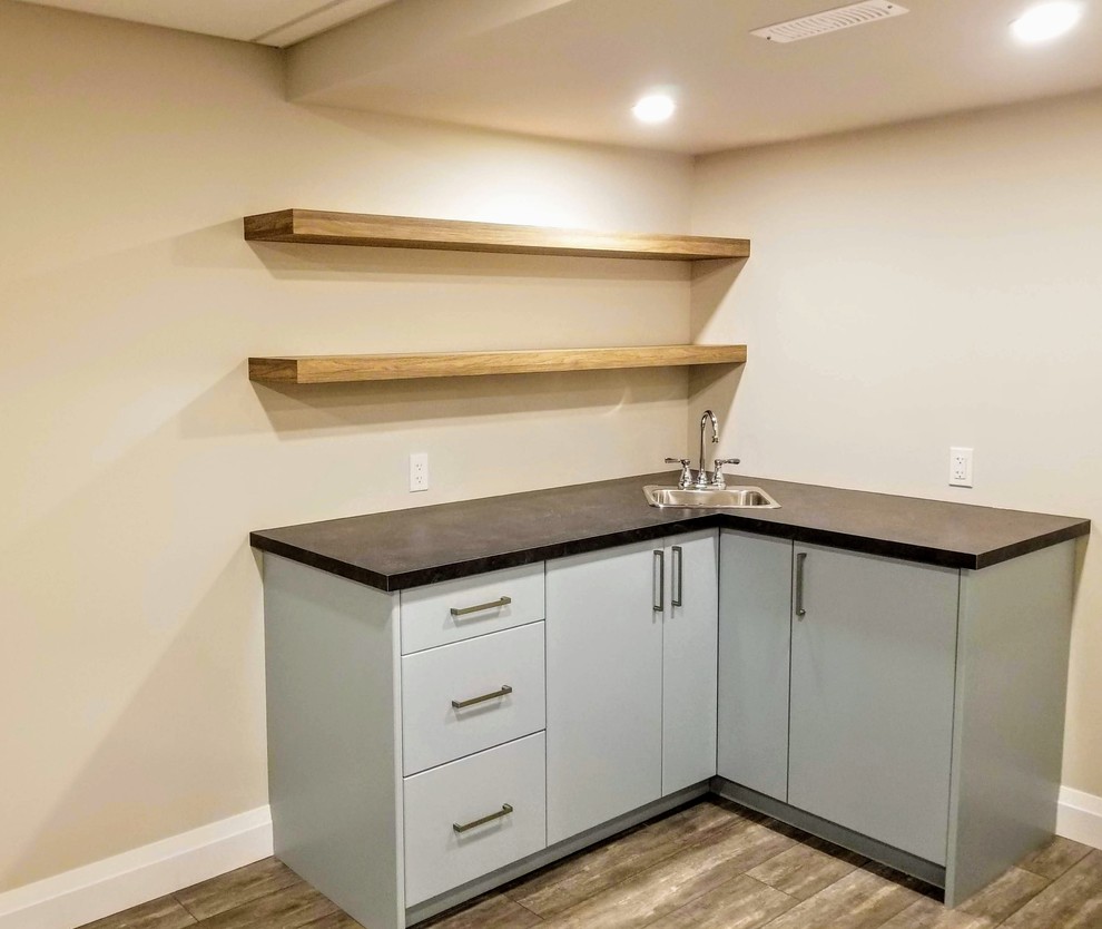 Home bar - large traditional l-shaped vinyl floor and brown floor home bar idea in Toronto with blue cabinets, laminate countertops and black countertops