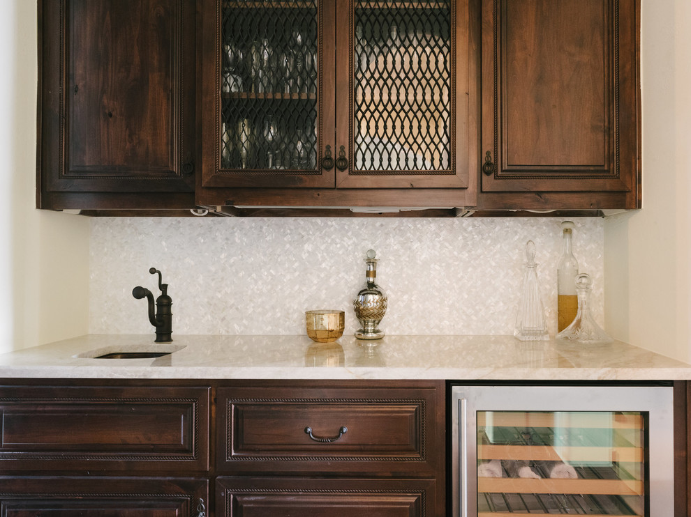 Small traditional galley wet bar in Austin with a submerged sink, dark wood cabinets and medium hardwood flooring.