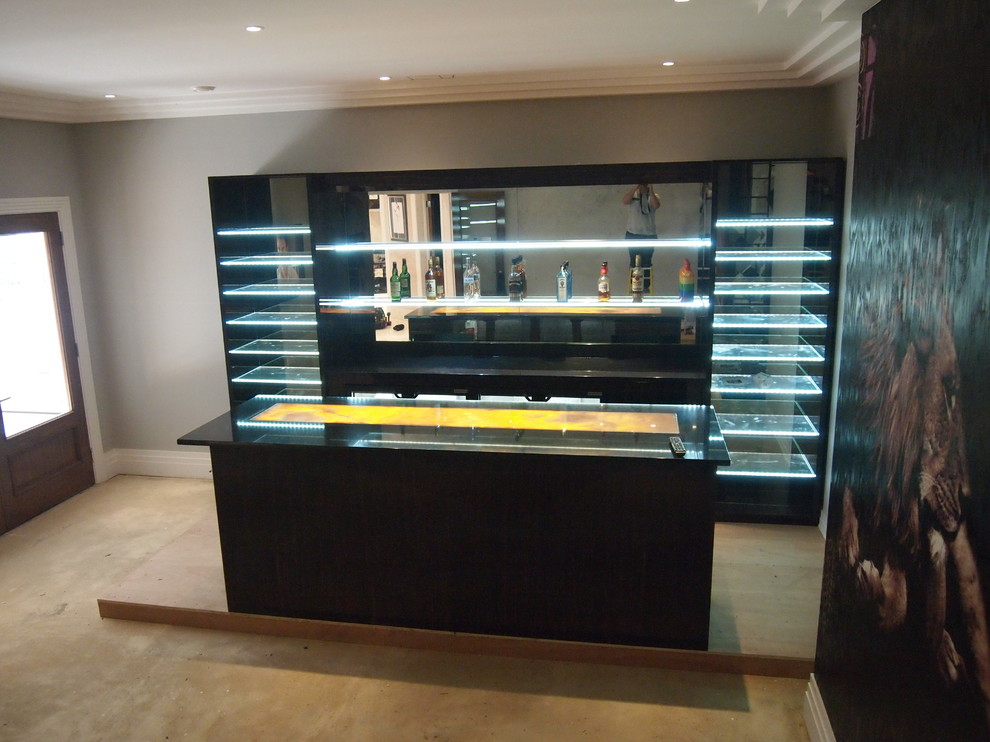 Design ideas for a large contemporary home bar in Surrey with open cabinets, dark wood cabinets and onyx worktops.