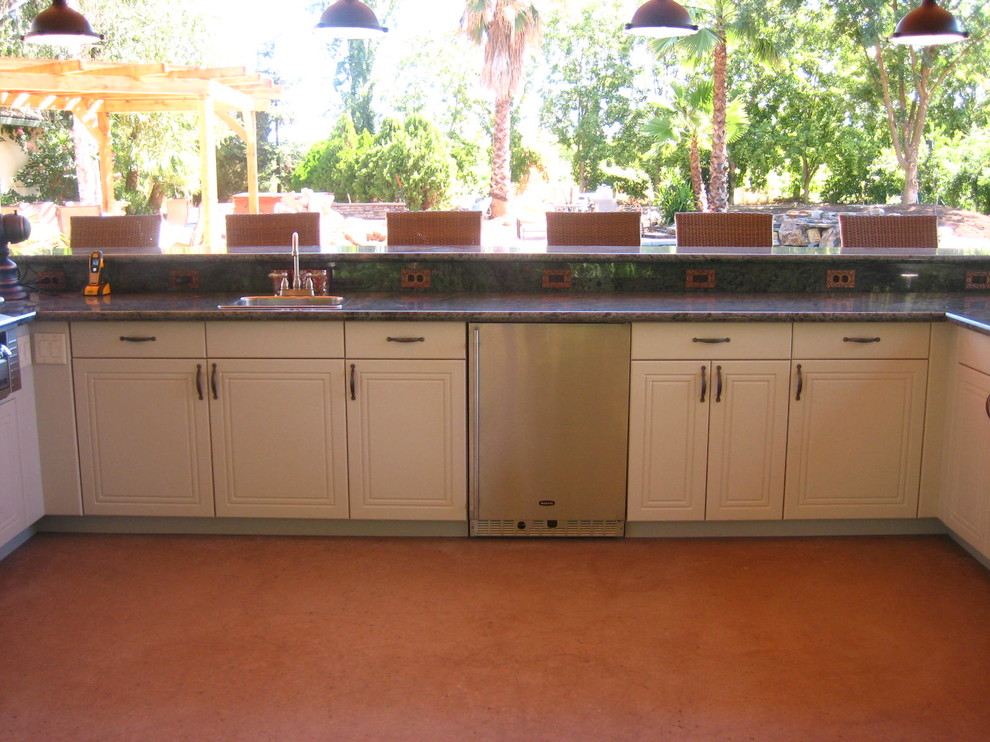 Photo of an expansive traditional u-shaped breakfast bar in Other with a built-in sink, flat-panel cabinets, white cabinets, engineered stone countertops and orange floors.