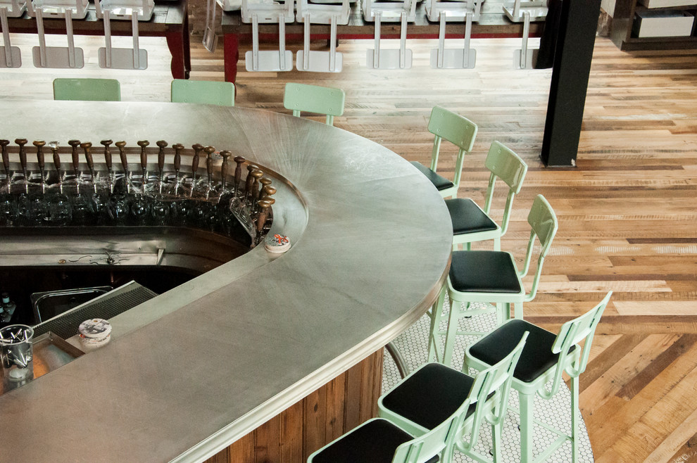 Immagine di un grande bancone bar industriale con nessun'anta, ante in legno bruno, top in zinco e parquet scuro