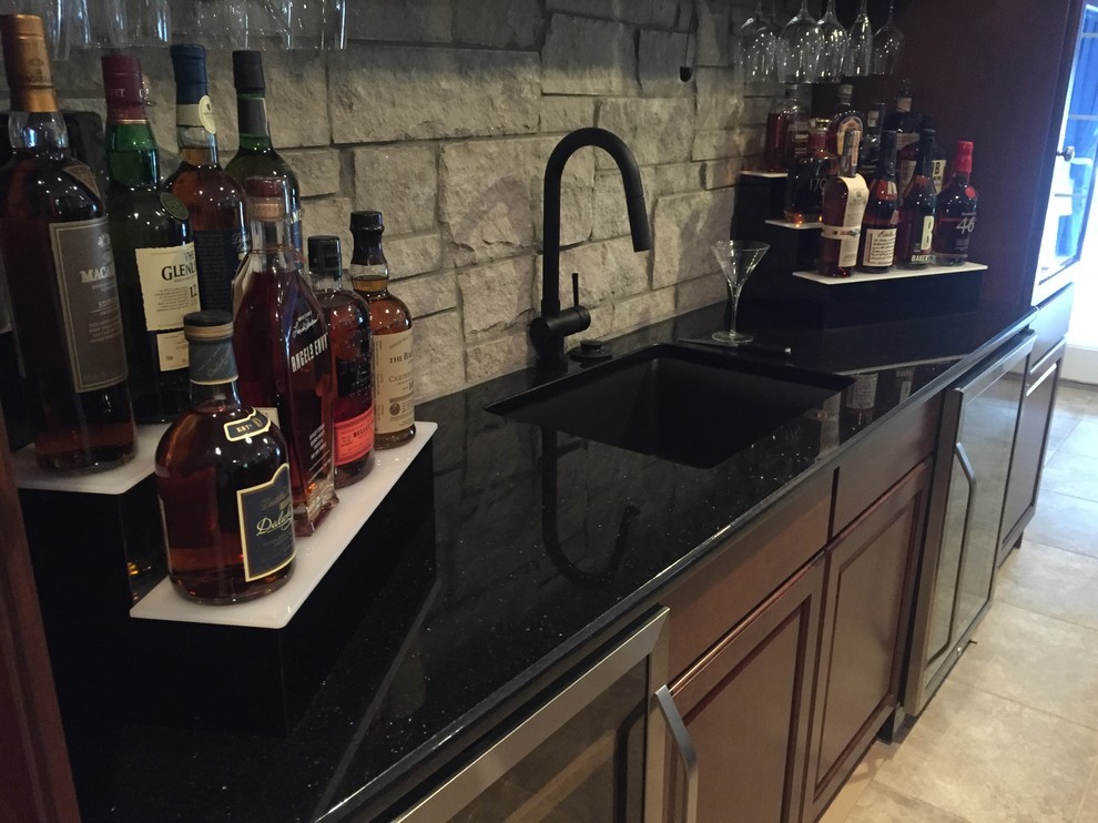 Example of a mid-sized transitional travertine floor seated home bar design in Philadelphia with an undermount sink, recessed-panel cabinets, medium tone wood cabinets, granite countertops, gray backsplash and stone tile backsplash