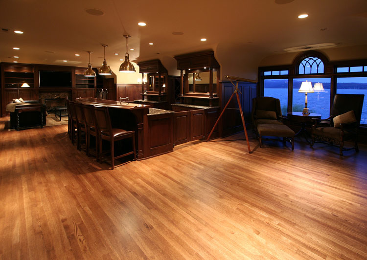 Foto de bar en casa con barra de bar de galera de estilo americano con puertas de armario de madera en tonos medios, encimera de granito y suelo de madera en tonos medios