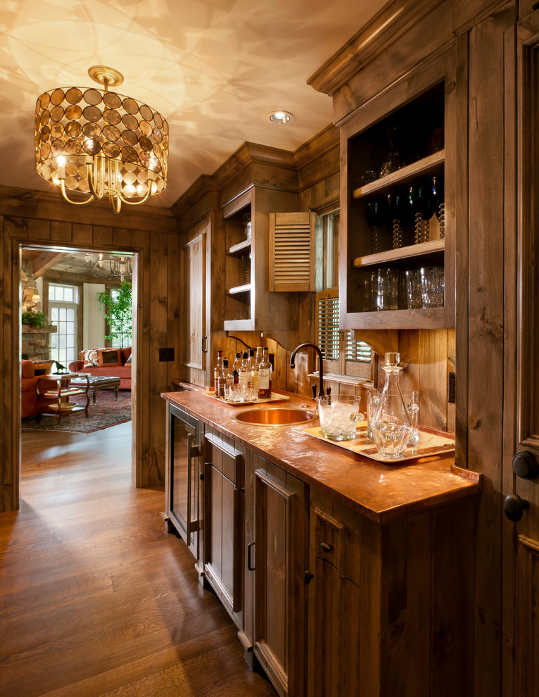 Inspiration for a traditional single-wall wet bar in Milwaukee with dark hardwood flooring, a built-in sink, recessed-panel cabinets and dark wood cabinets.