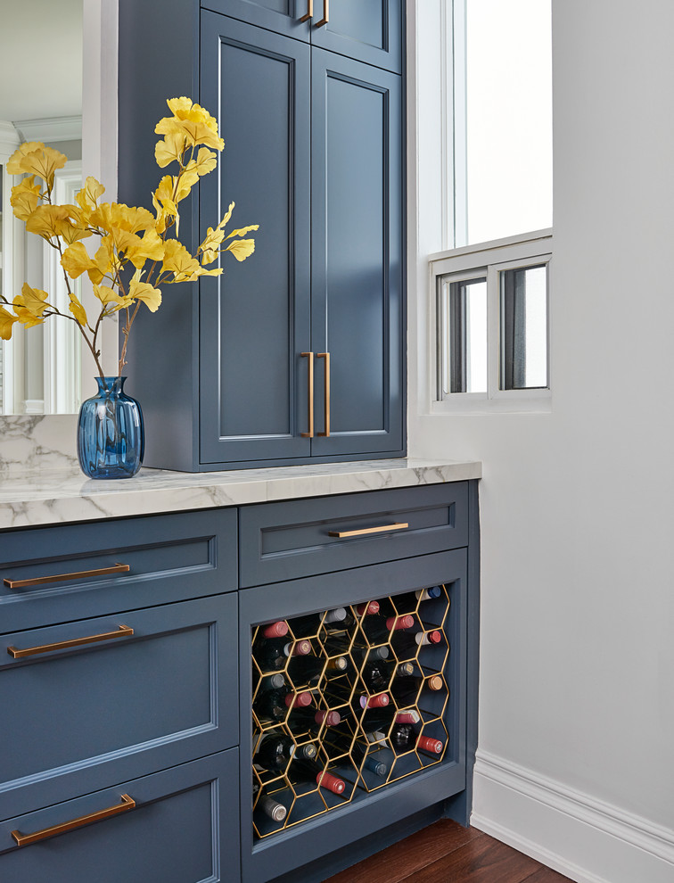 Imagen de bar en casa tradicional con armarios estilo shaker, puertas de armario azules, encimera de mármol, encimeras blancas, suelo de madera oscura y suelo marrón