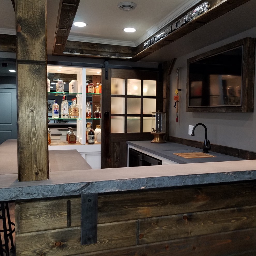 Foto de bar en casa con barra de bar en U actual grande con fregadero integrado, armarios tipo vitrina, encimera de cemento y salpicadero de madera