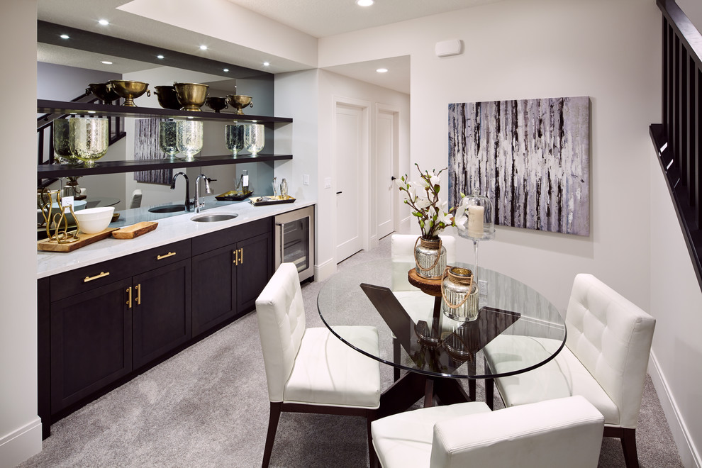 This is an example of a medium sized traditional single-wall wet bar in Calgary with carpet, a submerged sink, shaker cabinets, dark wood cabinets, marble worktops, mirror splashback and grey floors.
