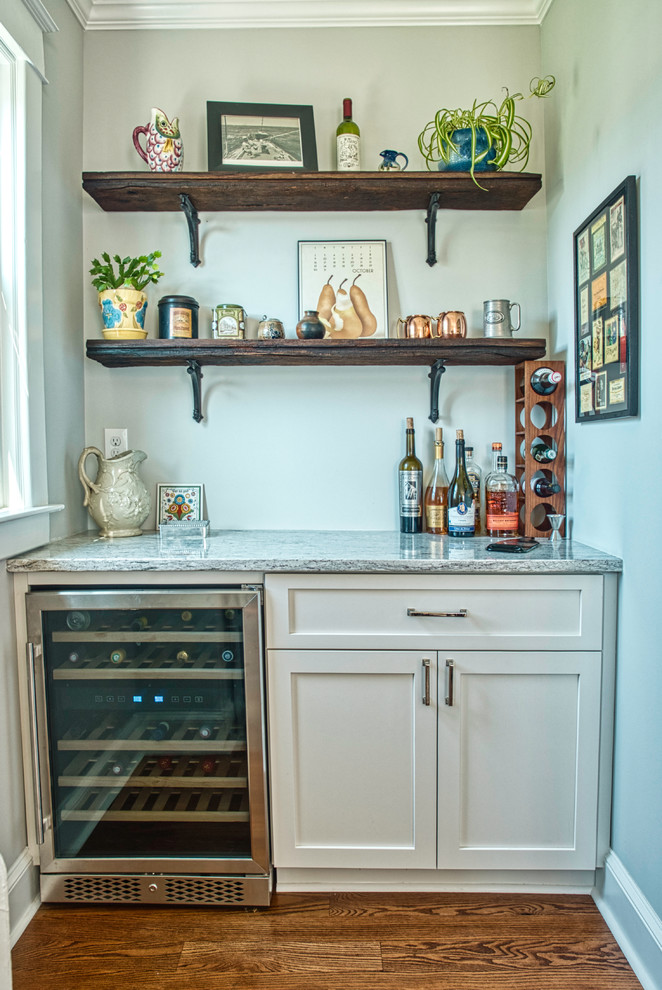 Inspiration for a small traditional single-wall home bar in Baltimore with shaker cabinets, white cabinets, granite worktops, medium hardwood flooring, brown floors and grey worktops.