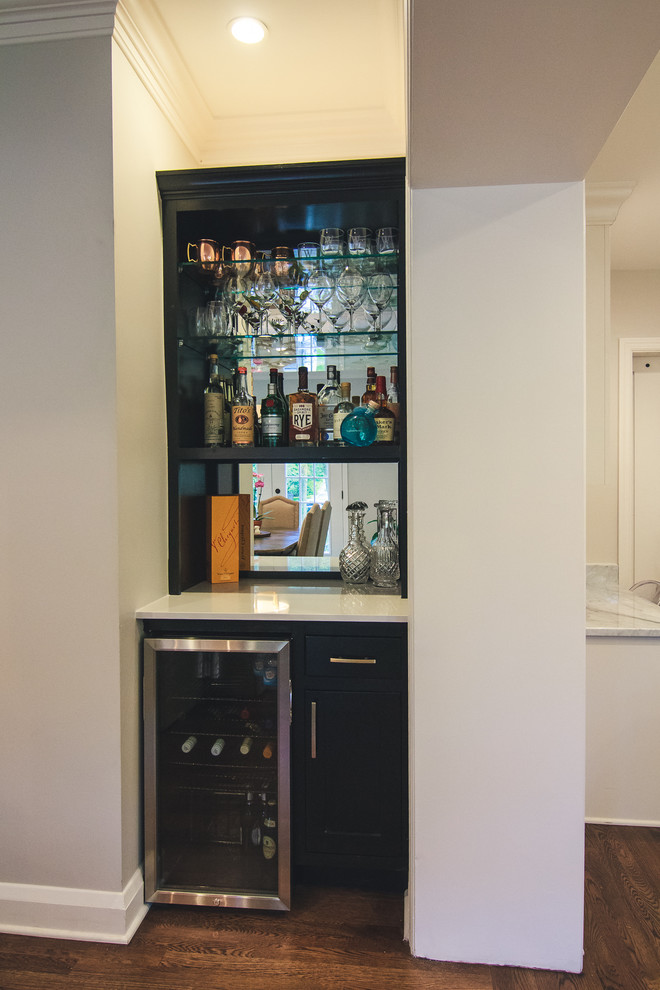 Imagen de bar en casa con fregadero lineal clásico pequeño sin pila con armarios estilo shaker, puertas de armario negras, encimera de cuarzo compacto, salpicadero con efecto espejo, suelo de madera en tonos medios y suelo marrón