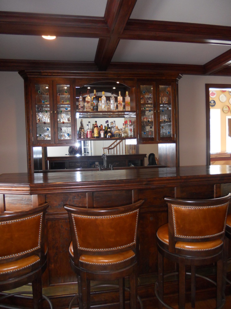 Idee per un bancone bar classico di medie dimensioni con ante a filo, ante in legno bruno, top in legno, paraspruzzi a specchio e pavimento in legno massello medio