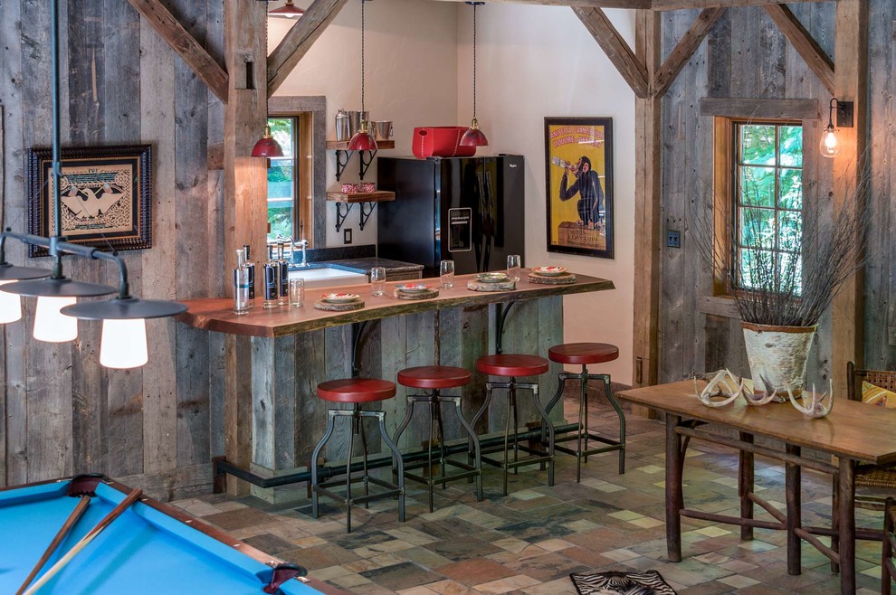 Esempio di un bancone bar rustico di medie dimensioni con top in legno, pavimento in ardesia, ante in legno scuro, pavimento grigio e top marrone
