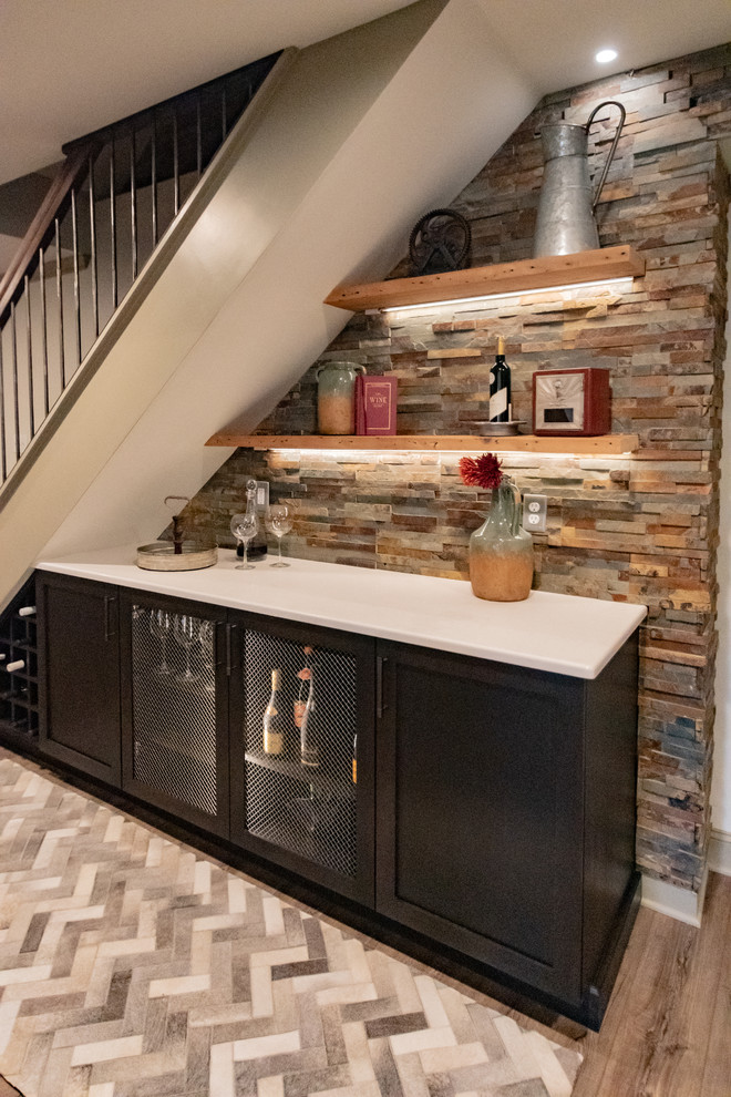 This is an example of a small rustic single-wall home bar in Philadelphia with no sink, shaker cabinets, dark wood cabinets, quartz worktops, multi-coloured splashback, light hardwood flooring, brown floors and white worktops.