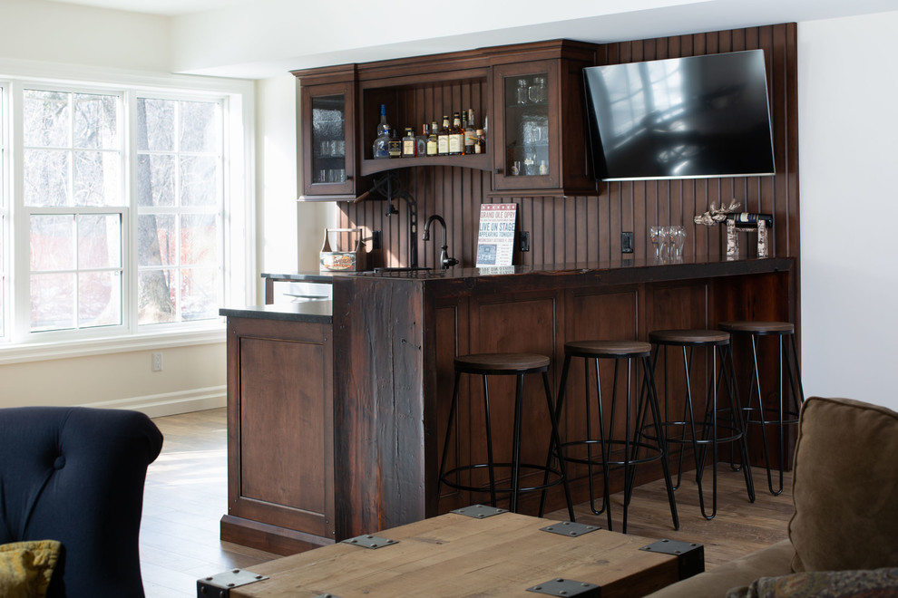 Inspiration for a mid-sized rustic l-shaped medium tone wood floor and brown floor seated home bar remodel in Toronto with glass-front cabinets, distressed cabinets, wood countertops, brown backsplash, wood backsplash, brown countertops and an undermount sink
