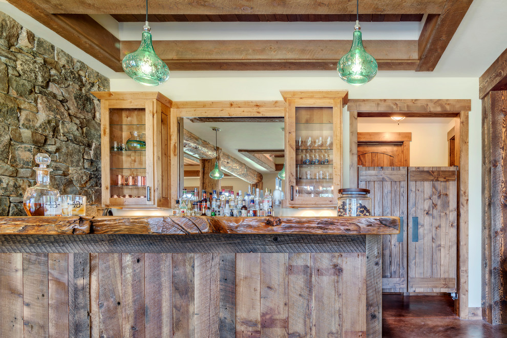 Modelo de bar en casa con barra de bar en U rural grande con puertas de armario con efecto envejecido, encimera de madera, suelo de cemento, suelo marrón y encimeras marrones