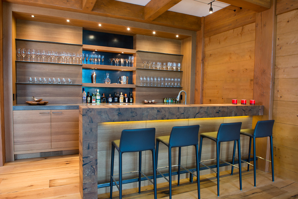Cette photo montre un bar de salon parallèle montagne en bois brun avec des tabourets, un placard à porte plane et un sol en bois brun.