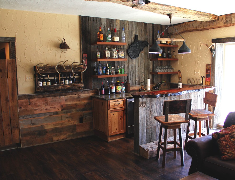 Cette photo montre un bar de salon linéaire montagne en bois vieilli de taille moyenne avec des tabourets, un évier encastré, un placard à porte shaker, un plan de travail en granite, une crédence marron et un sol en vinyl.