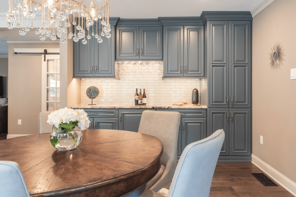 This is an example of a small traditional single-wall home bar in Philadelphia with no sink, raised-panel cabinets, blue cabinets, granite worktops, white splashback, glass tiled splashback, dark hardwood flooring, brown floors and multicoloured worktops.