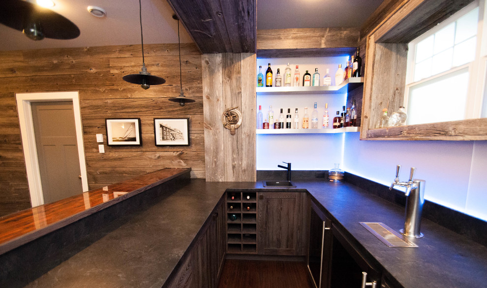 Foto di un grande bancone bar rustico con lavello da incasso, ante in stile shaker, ante in legno chiaro, top in cemento, paraspruzzi blu, paraspruzzi con lastra di vetro, parquet scuro e pavimento marrone