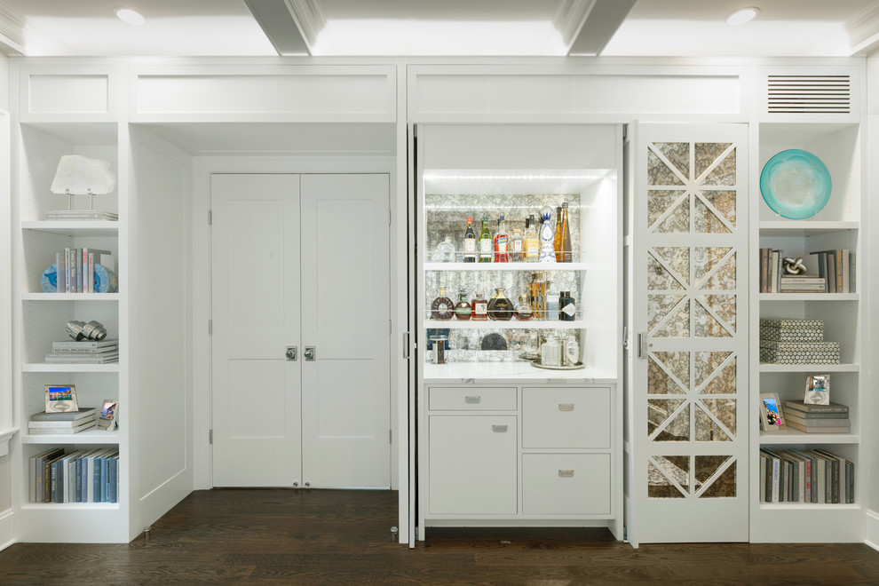 This is an example of a small beach style single-wall home bar in New York with dark hardwood flooring, brown floors, no sink, flat-panel cabinets, white cabinets, white worktops, quartz worktops and mirror splashback.