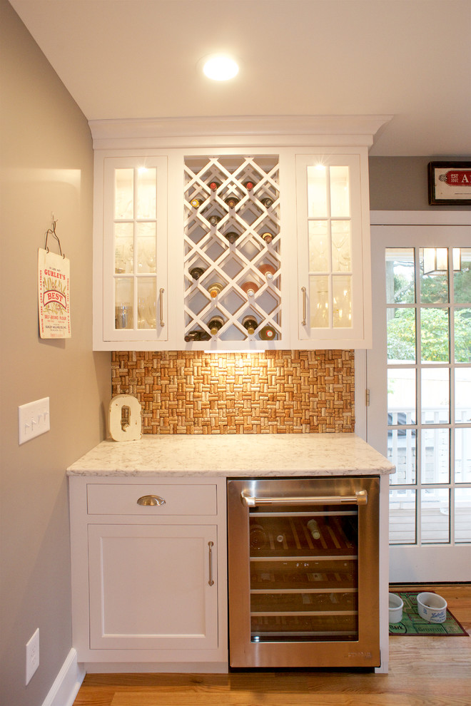 This is an example of a small coastal single-wall dry bar in New York with glass-front cabinets, white cabinets, engineered stone countertops, orange splashback, medium hardwood flooring and white worktops.