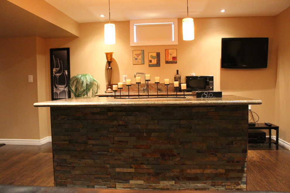 Cette image montre un bar de salon parallèle traditionnel de taille moyenne avec un sol en bois brun, des tabourets, un évier encastré, un plan de travail en granite, une crédence beige et une crédence en dalle de pierre.