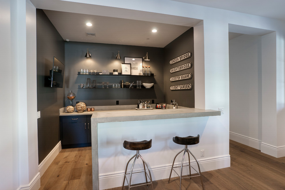 Esempio di un bancone bar classico di medie dimensioni con ante nere, top in cemento, pavimento in legno massello medio, pavimento marrone e top grigio