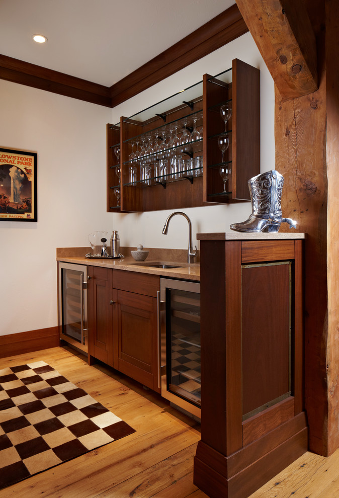 Rustik inredning av en mellanstor linjär hemmabar med vask, med en undermonterad diskho, skåp i mörkt trä, mellanmörkt trägolv, bänkskiva i kvarts, brunt golv och luckor med infälld panel