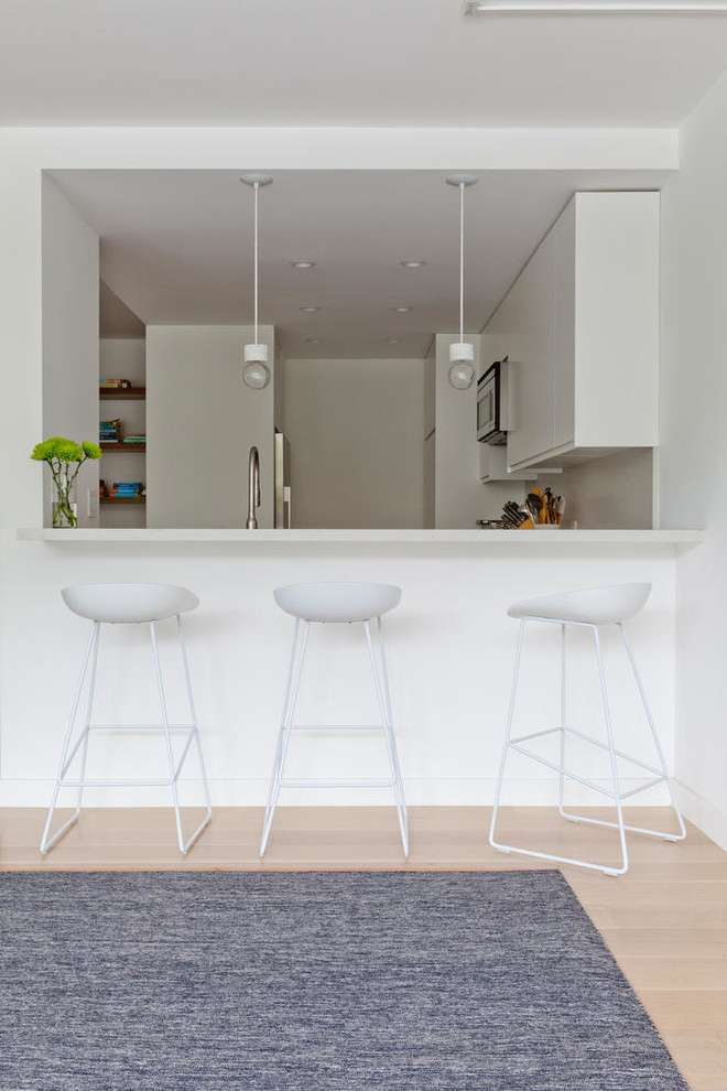 Inspiration för en stor minimalistisk hemmabar, med vita skåp och ljust trägolv