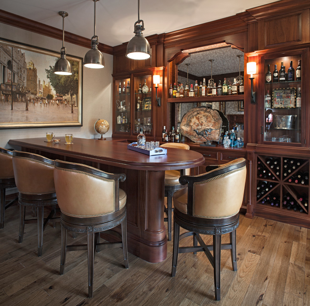 Imagen de bar en casa con barra de bar tradicional con puertas de armario de madera en tonos medios, salpicadero con efecto espejo, suelo de madera en tonos medios y suelo marrón