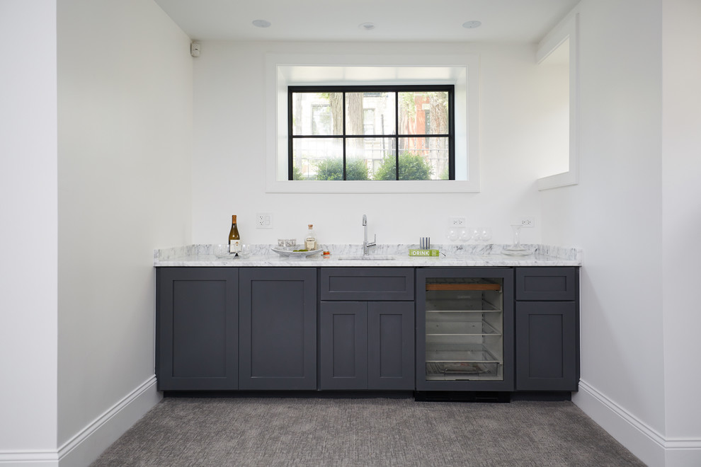 Transitional carpeted and beige floor home bar photo in Chicago with an undermount sink, shaker cabinets, gray cabinets, marble countertops, gray backsplash, marble backsplash and gray countertops