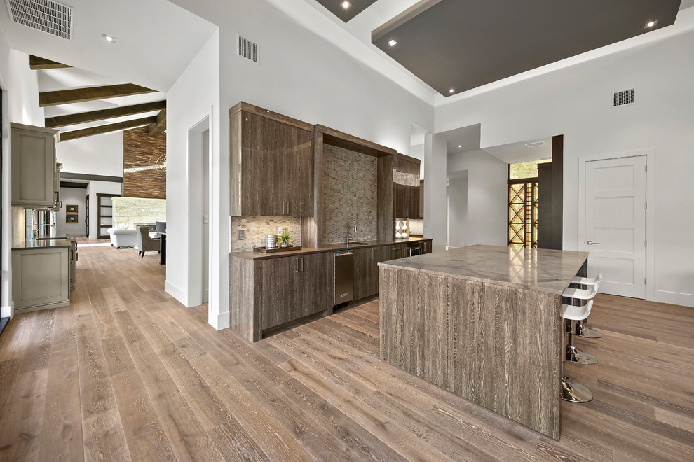 Large transitional galley porcelain tile and brown floor seated home bar photo in Austin with a drop-in sink, flat-panel cabinets, brown cabinets, beige backsplash and marble backsplash
